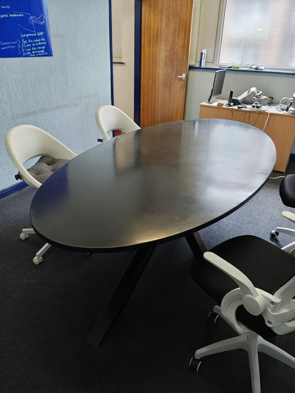 Racetrack-shaped polished concrete dining table with oval ends and steel base