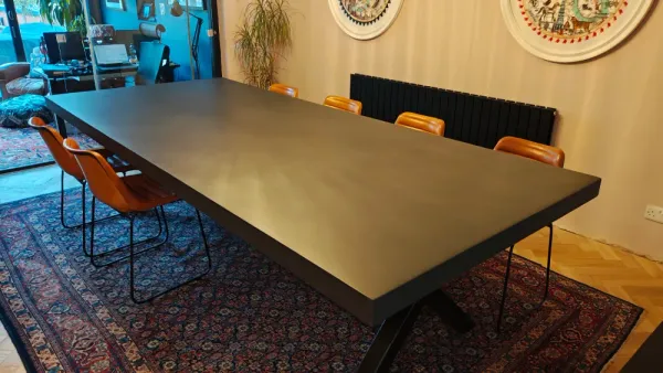 Concrete handcrafted dining table with smooth tabletop and steel pedestal base